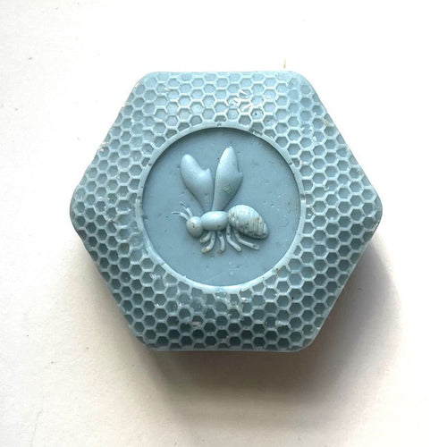Hexagonal blue soap with bee and honeycomb design on a white background